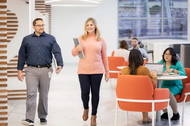 Two people walking through casual sitting area in office