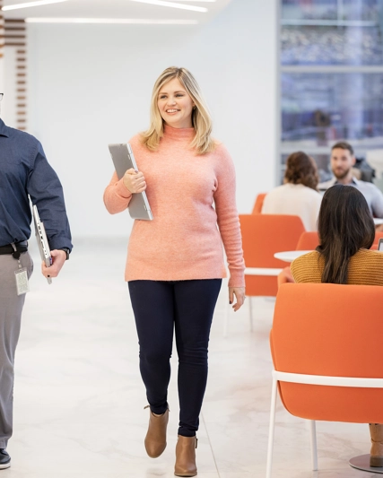 Two people walking through casual sitting area in office